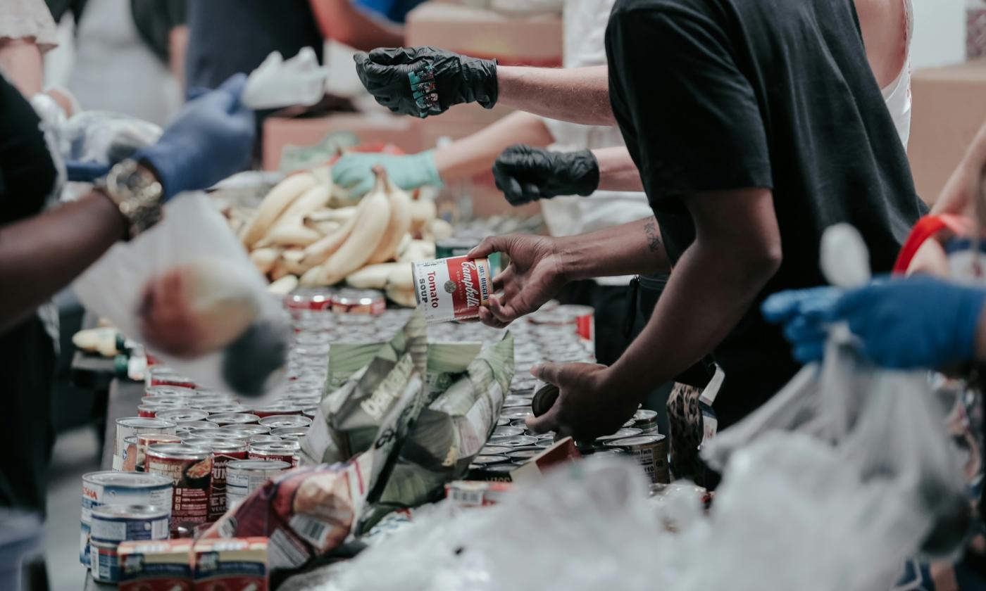 Volunteers separate cans and other goods on a long table.