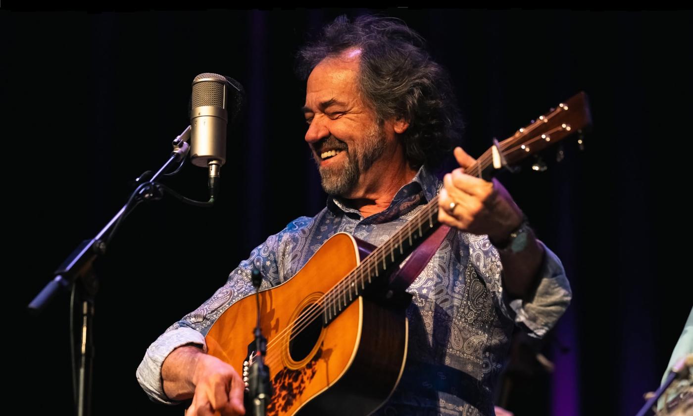 Dan Tyminski on a black stange with his guitar