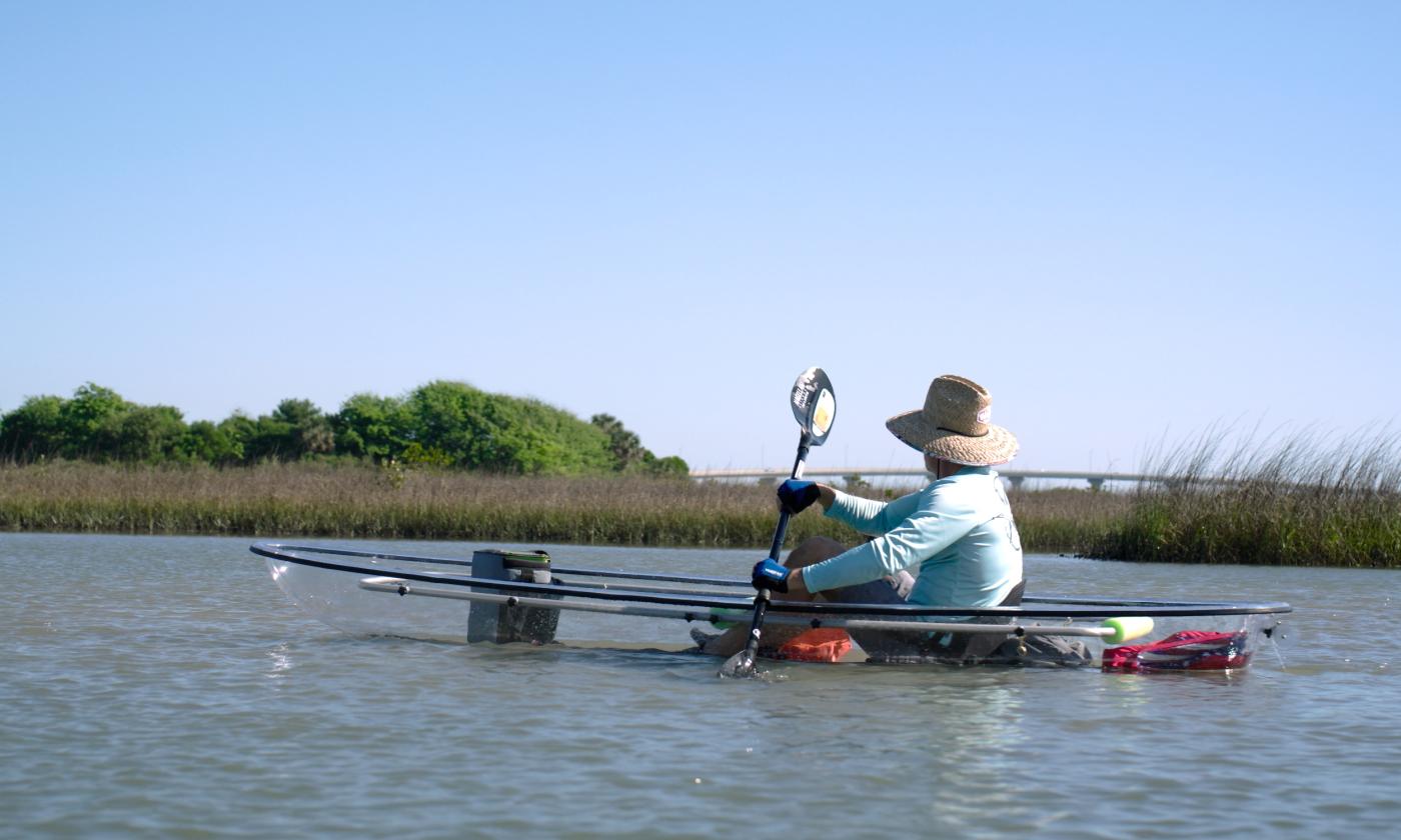 A kayaker in a transparent kayak with a view of Vilano Bridge