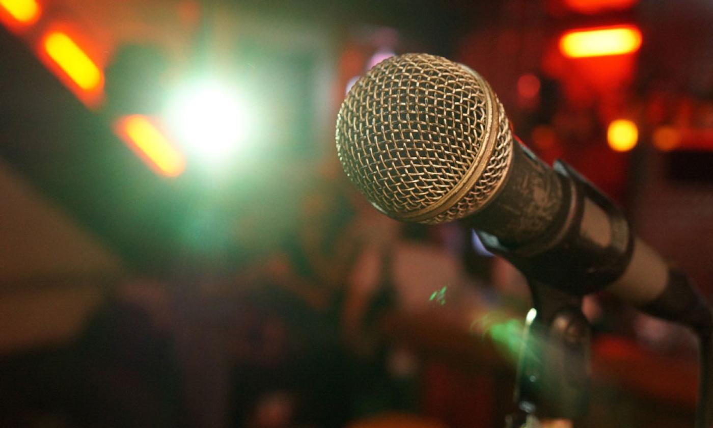 Comedians face a microphone, lights, and an audience seeking laughter. 