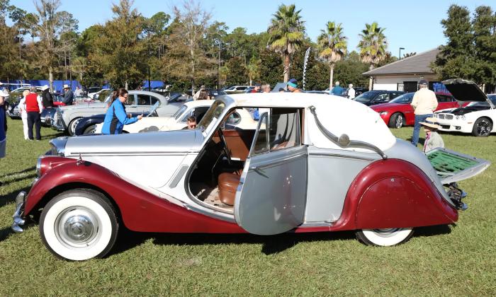 An early two-toned silver and red with suicide doors on the lawn at a car show