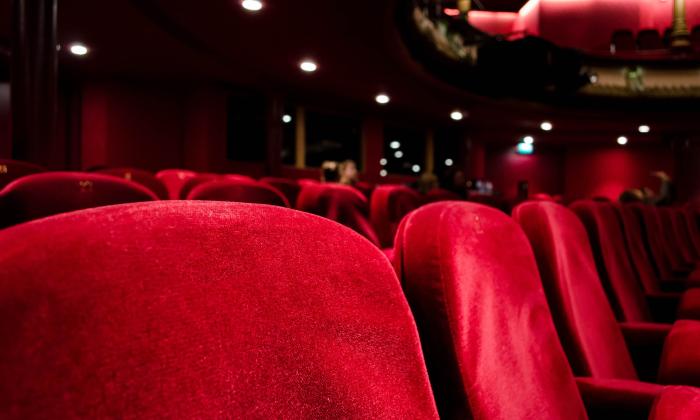 Red theatre seats in an auditorium in front of the stage. 