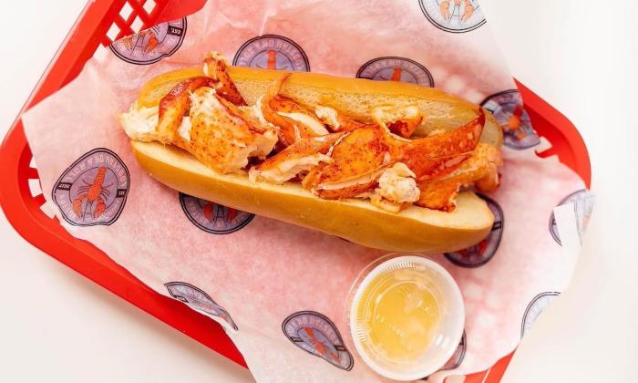 A lobster roll in a red basket with a side of butter