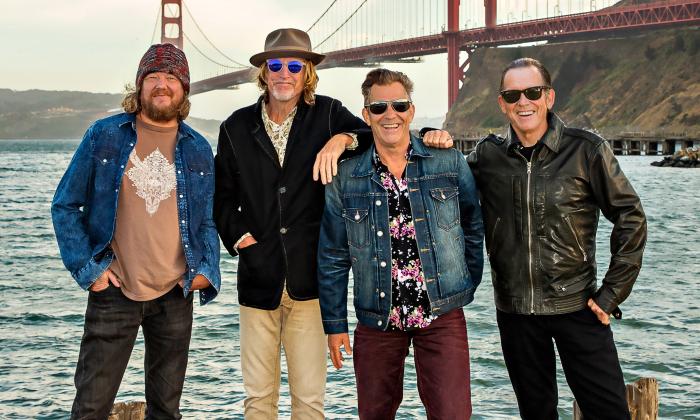 Four men, Tommy Castro and the Painkillers, stand in front of the Golden Gate Bridge