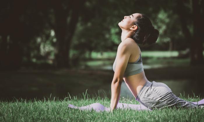 A woman in the upward facing dog pose, practicing yoga outside on a lawn