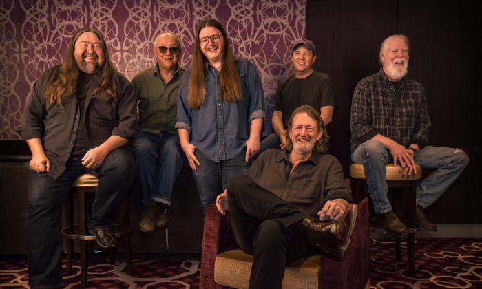 The members of Widespread Panic, standing and sitting in a darkened room