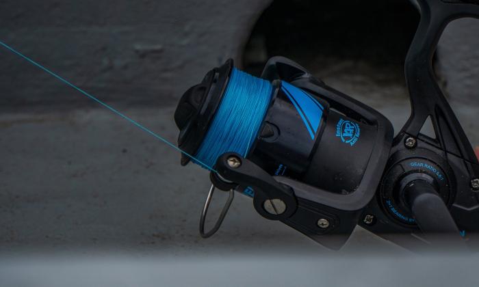A blue fishing reel is positioned inside a boat. 