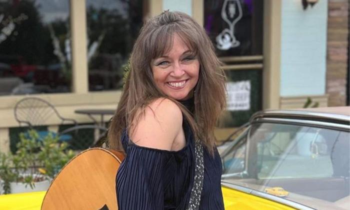 Michelle Ingrhman with her guitar in front of a yellow car