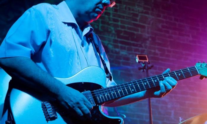 The guitarist for the band Unlimited Devotion performs on stage with a microphone in front of his body