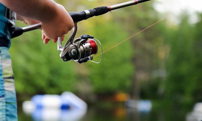 A man casts his fishing line in water. 