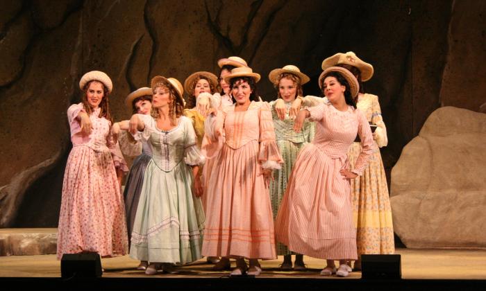 A group of women opera performers, on stage in a performance of La Bohème