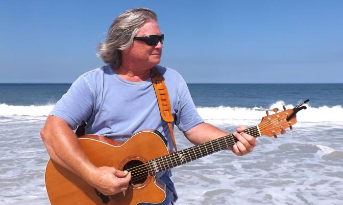 Jim Lamb with his guitar in front of the atlantic ocean