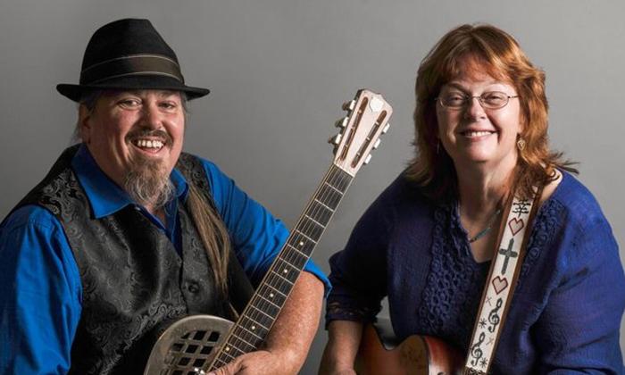 Musicians Cindy Bear and Robert smiling, holding instruments