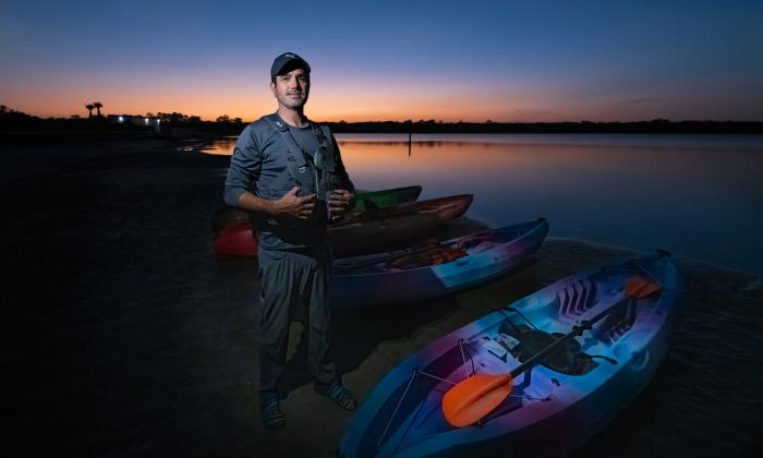 Ben Brandao, owner of GeoTrippin' standing next to kayaks at sunset