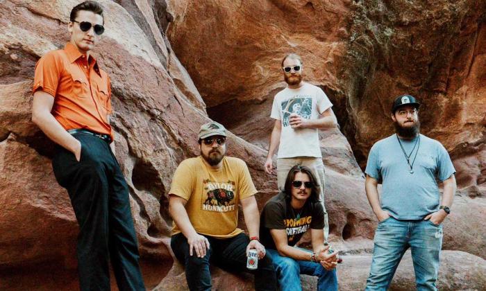 Bandmates from The Red Clay Strays pose near oversized rocks and boulders. 