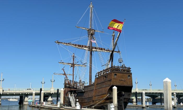 The Nao Trinidad tall ship sits by the dock, next to the Bridge of Lions, during the peak hours of the day