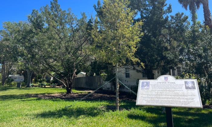 The shaded green space of Twine neighborhood Park in St. Augustine, FL on a sunny day. Twine Park historical marker is visible at the bottom of the image.