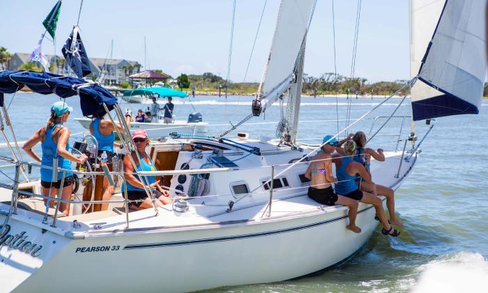 An all-female sailboat crew, sail a boat along the waterfront