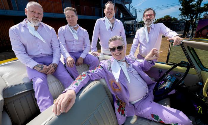 Bandmates from Me First and The Gimmie Gimmies pose in purple dress shirts and pants with matching neckties. 
