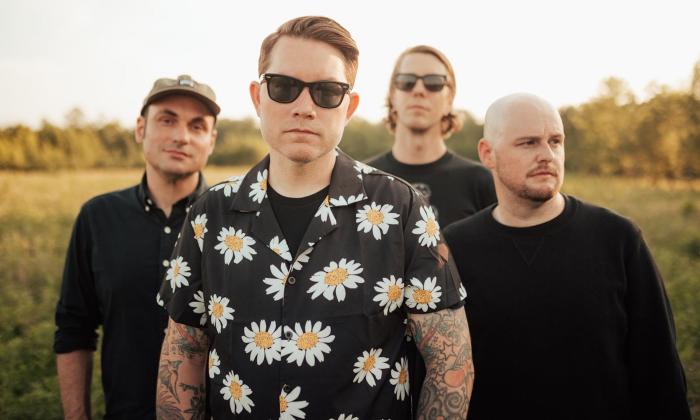Bandmates from Hawthorne Heights pose in front of a meadow. 