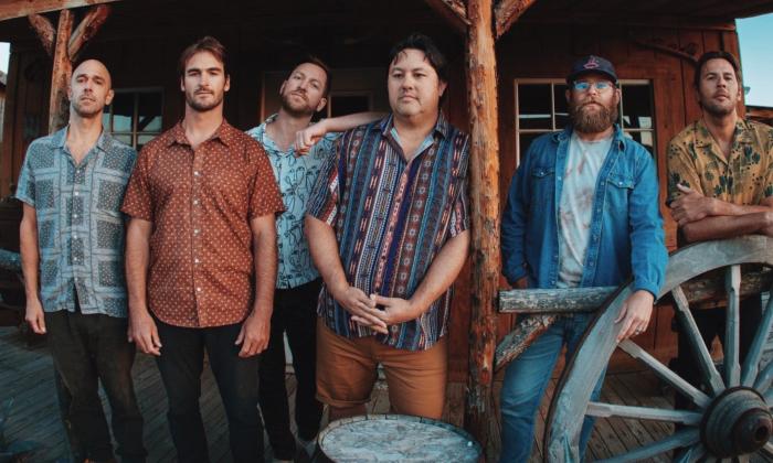 Bandmates from Iration and Pepper pose next to a wagon wheel. 