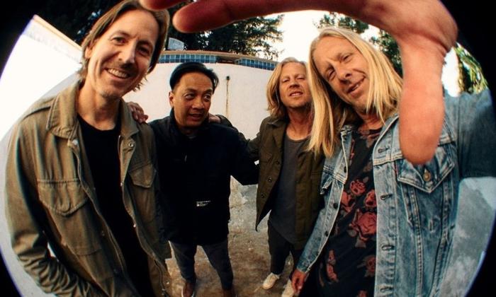 Bandmates from Switchfoot smile and pose in front of a fisheye lens. 