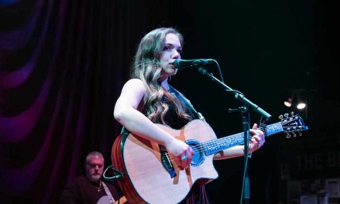 Singer and songwriter Paige King Johnson on stage with a guitar