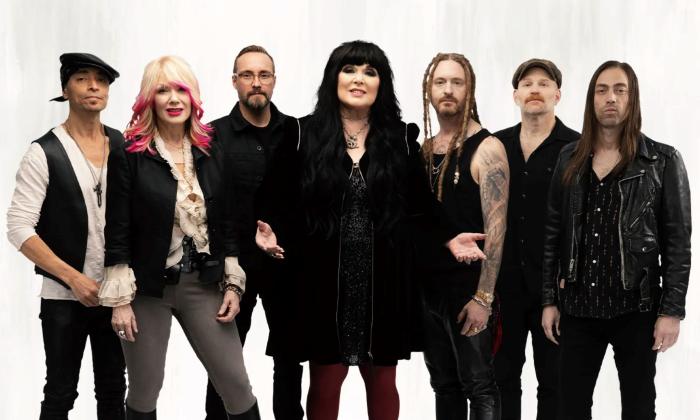 Bandmates from Heart wear black and pose in front of a white backdrop.