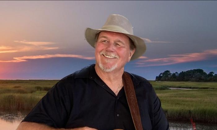 Singer-songwriter Jim Bickerstaff in a hat, smiling, with hills behind him
