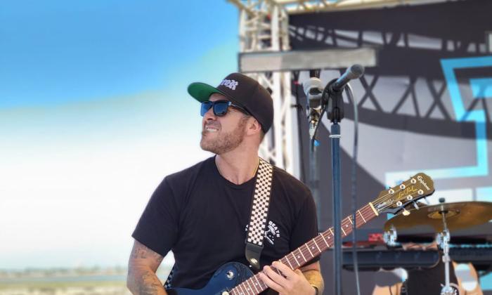 Musician Kyle Smith playing guitar instage, outside