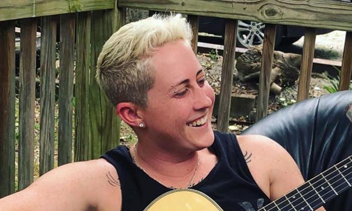 Songwriter Kristen Merlin smiling, playing her guitar, outside
