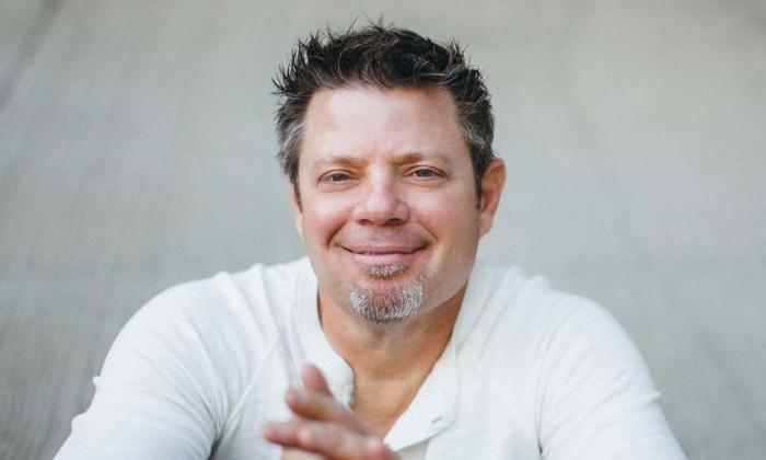 Songwriter Rodney Clawson, smiling, sitting in front of a white wall