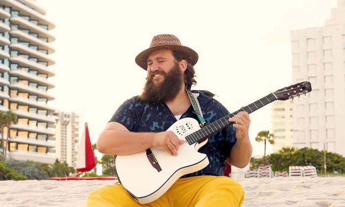 Singer-songwriter Zach Deputy playing his guitar, in a beach.