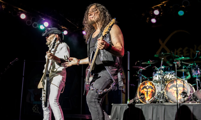 Bandmates from Queensryche clutch their guitars and perform live on stage.