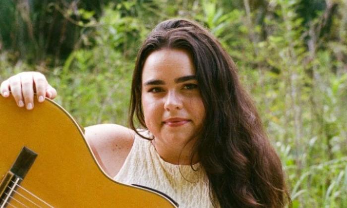 Singer songwriter Alyce Doty outside, with her guitar