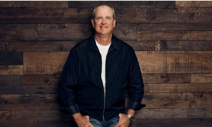 Songwriter Monty Criswell standing in front of a brown wood wall