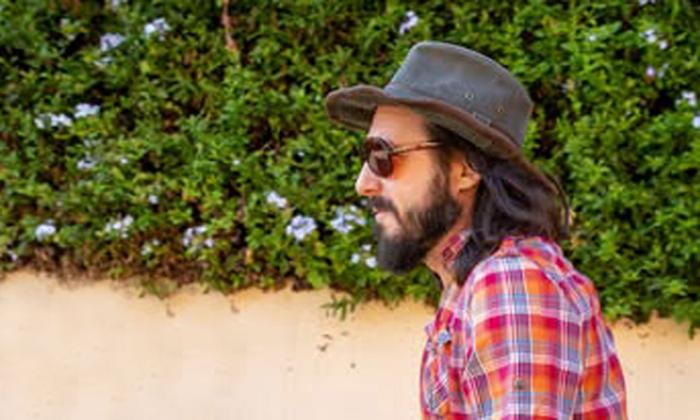 Songwriter-singer Paul Orehovec in black fedora standing in front of ivy covered wall