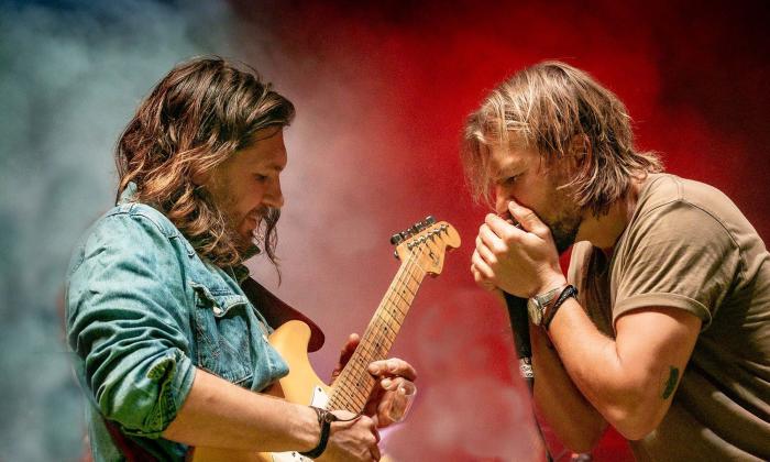 Teskey Brothers onstage, playing harmonica and guitar.