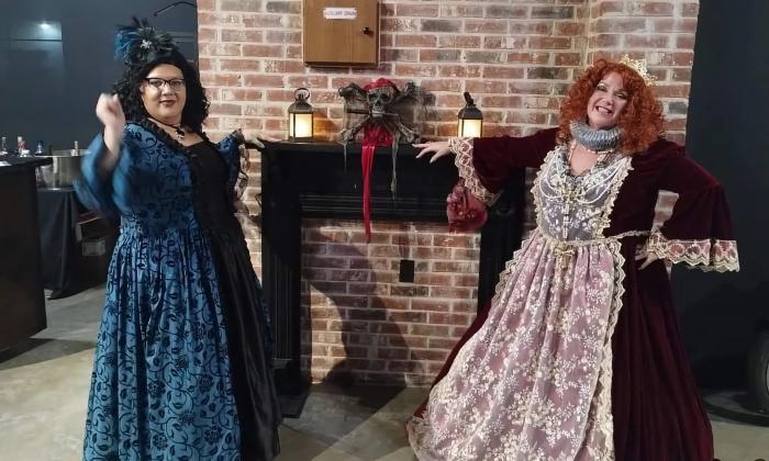 Two women, dressed in garb from the 1700s greet guests at the Blackbeard's Ball