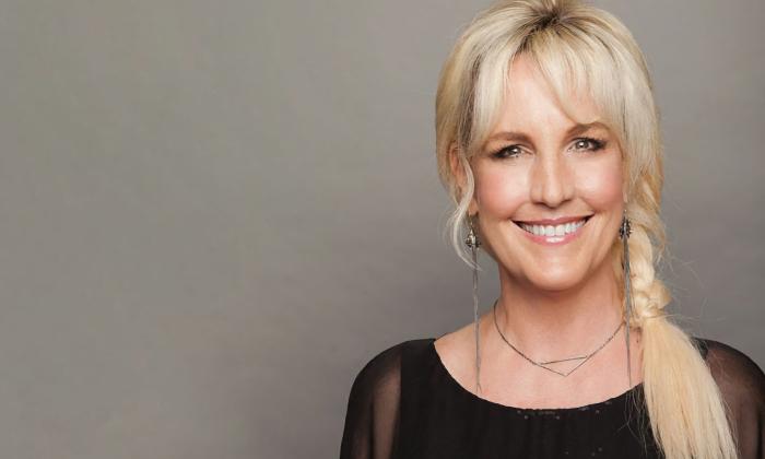Erin Brockovich smiling in front of a grey screen