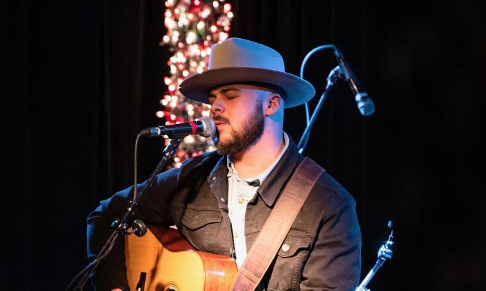 A singer on stage with his guitar, with decorative lights in the background