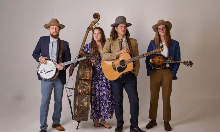 The four members of Remedy Tree, with their instruments, against a beige background