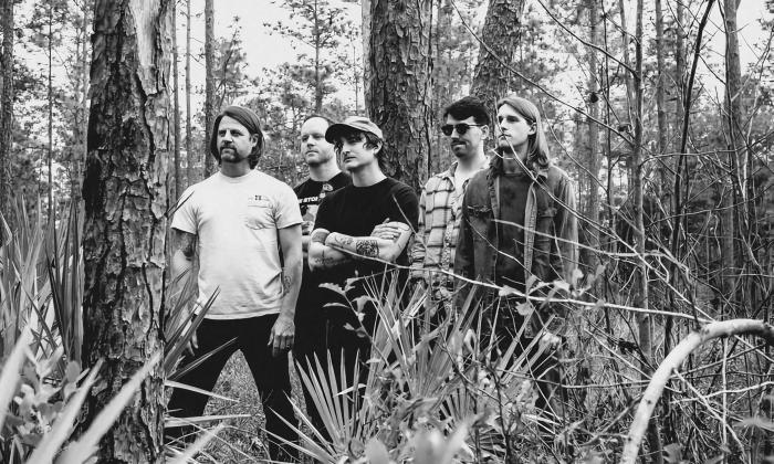 The five members of Supertwin, standing in a forest