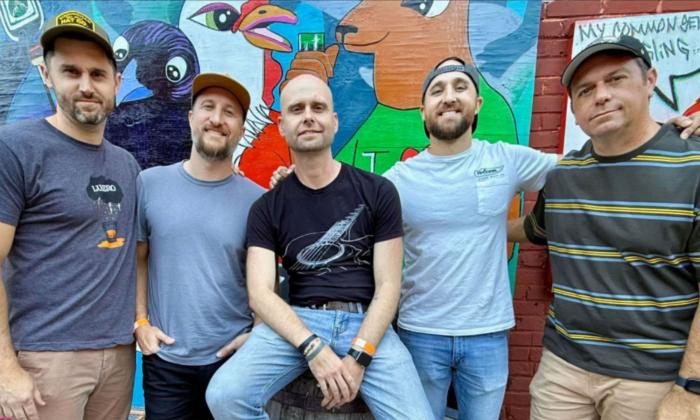 The band American Souvenir standing together in front of a colorful wall