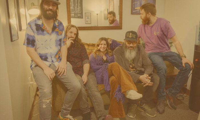Bandmates from Bearly Dead smile and pose together in a cozy room with a mirror.