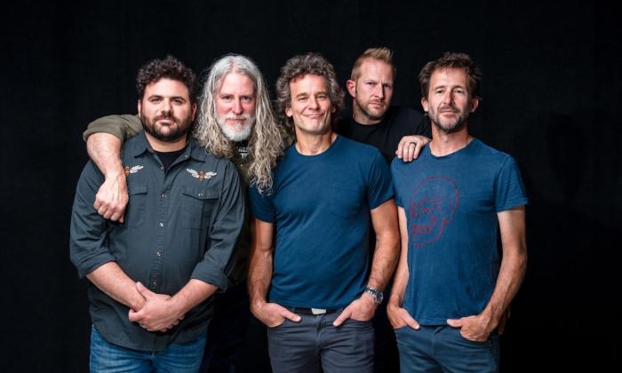 Bandmates from Carbon Leaf huddle together and pose in front of a black backdrop.
