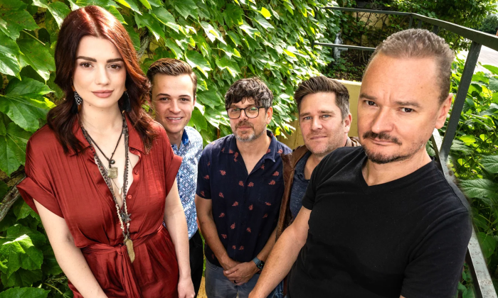Bandmates from Gaelic Storm smile and pose in front of a green backdrop.