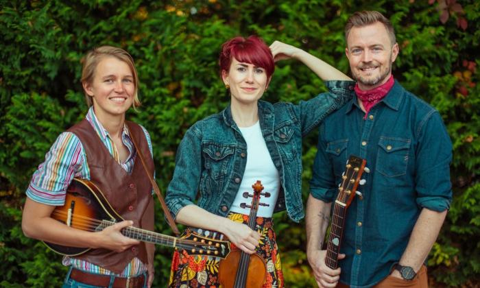 Bandmates from House of Hamill smile and pose in front of an oversized shrub.