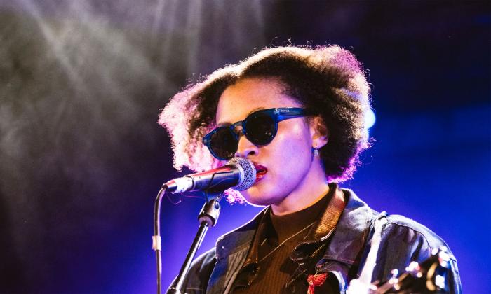 Singer songwriter Quiana Major onstage with guitar, wearing sunglasses
