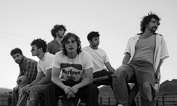 The six members of Ax and the Hatchetmen sitting outside on a picnic table